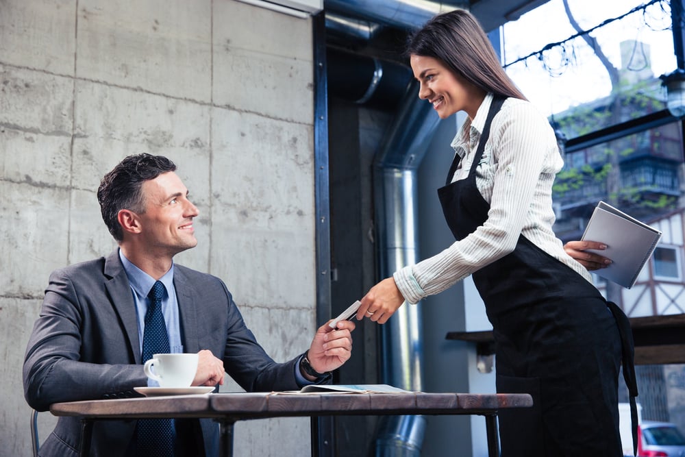 Happy man giving bank card to smiling female waiter in restaurant-1